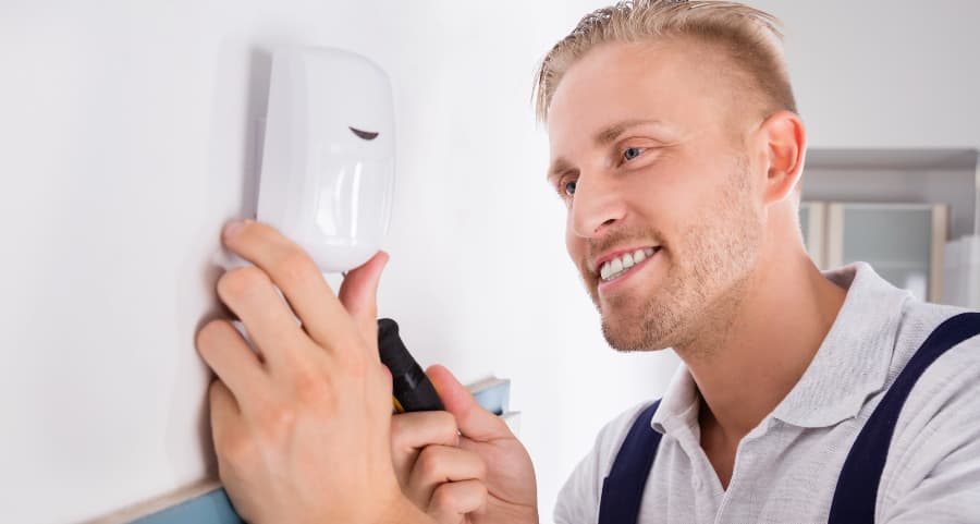 Man connecting a motion detector on a wall